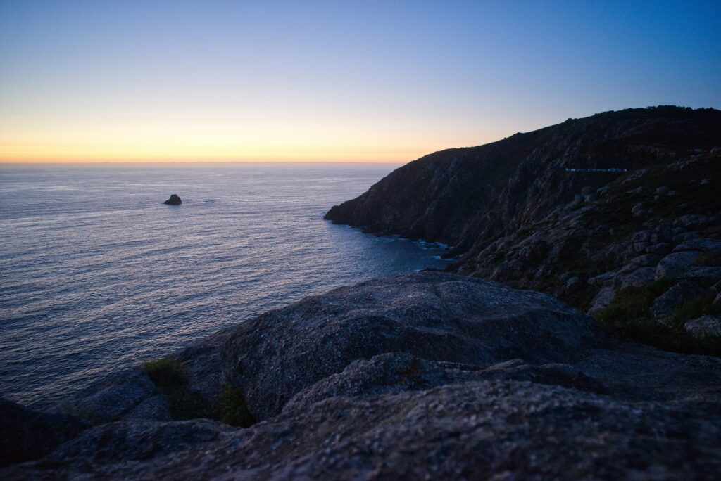 Dark rocky headland above a still sea at sunrise