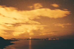 Golden clouds above a calm sea at sunset with a distant headland
