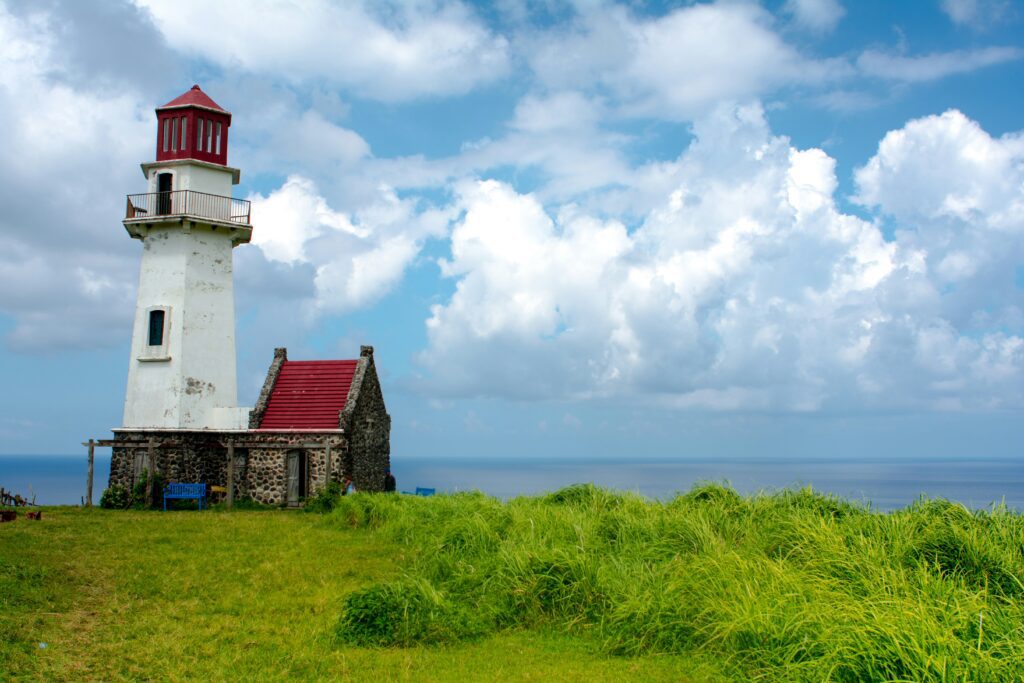 Red-roofed lighthouse and stone keeper's cottage above tall grass