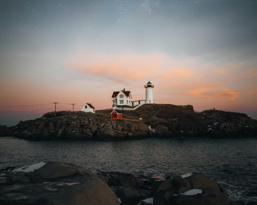 Nubble Lighthouse and keeper's house on a rocky island at twilight