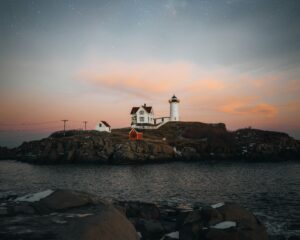 Nubble Lighthouse and keeper's house on a rocky island at twilight