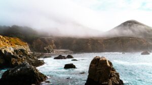 Fog rolling over a rugged coastline with waves breaking on rocks