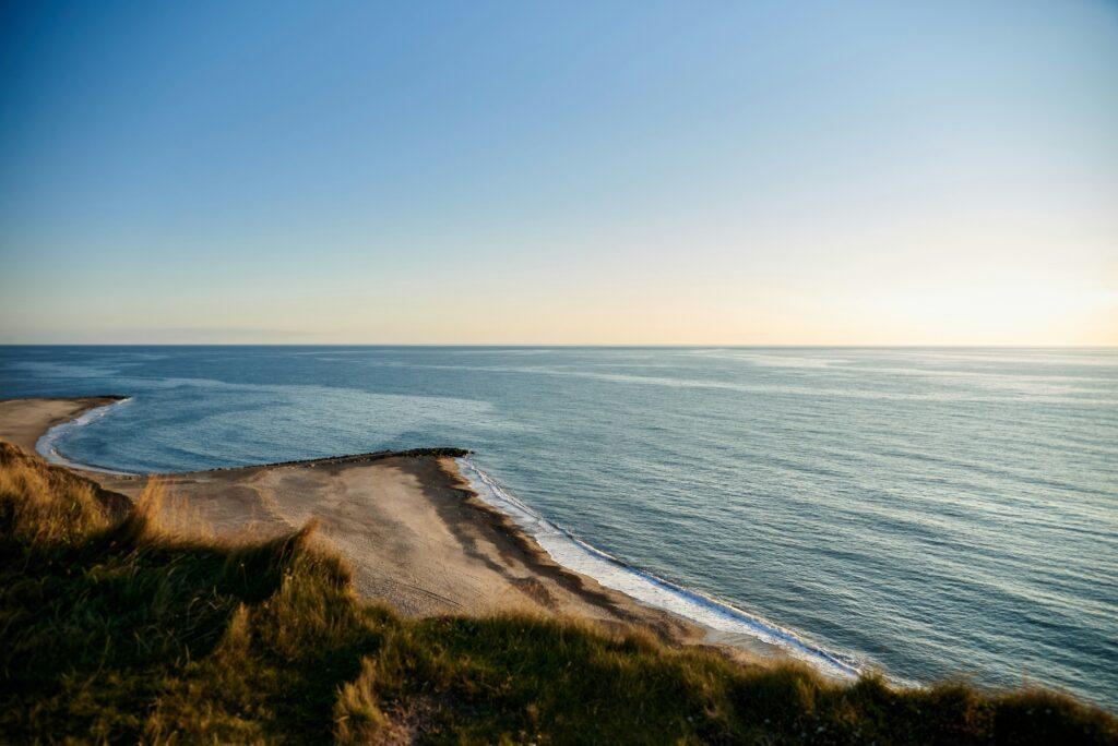 Long sandy spit curving into a calm sea at dawn