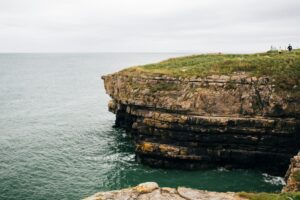 Layered limestone cliff jutting out over green water