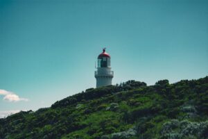 White lighthouse with a red lantern room on a grassy headland