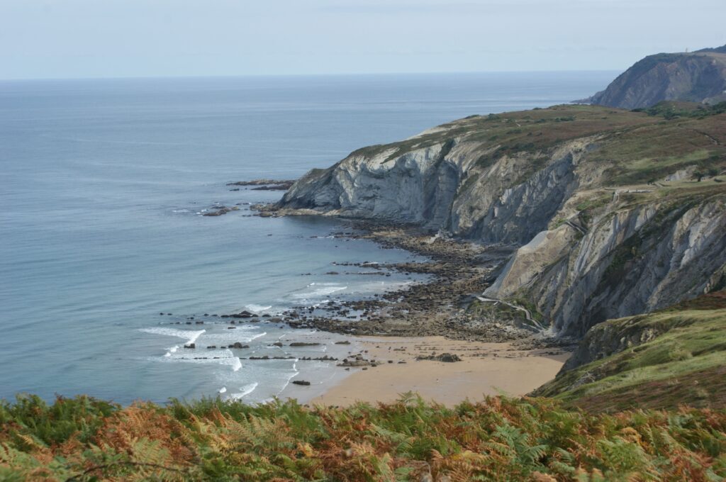 Layered rock cliffs above a rocky cove at low tide