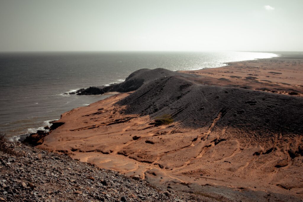 Bare reddish dune ridge above a shining sea