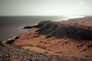 Bare reddish dune ridge above a shining sea