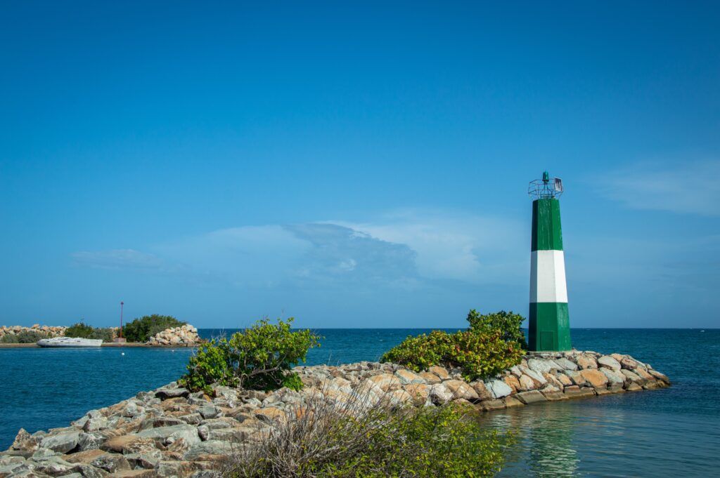 Green and white striped lighthouse on a rocky breakwater