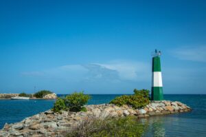 Green and white striped lighthouse on a rocky breakwater