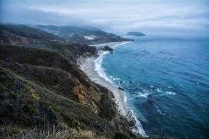 Blue dusk over a winding coastline with surf on a dark beach