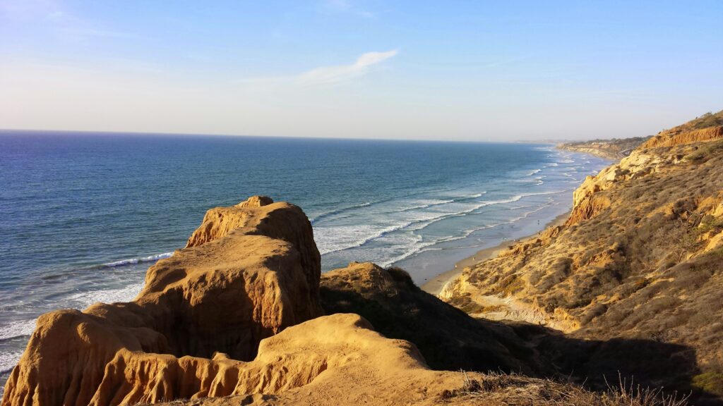 Eroded sandstone rocks above a long empty beach
