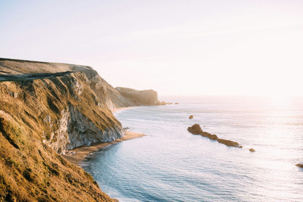 Pale grassy headland falling away to a calm sea in morning light