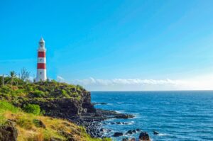 Red and white lighthouse on a grassy headland above the ocean